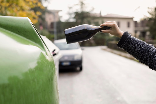 Woman throwing empty bottle in garbage can