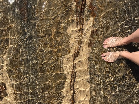 View from above of woman's feet in shallow water