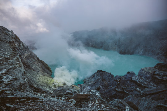 smoking sulfur mine beside acid lake on mount ijen at sunrise