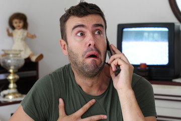 Man crying at home during phone conversation