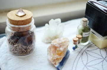 Mystical Peridot in a vial, healing crystals set up on a white cloth. Azurite berries in miniature vial. Crystal display, bohemian decorations on a brightly lit background. Fresh and colorful crystals