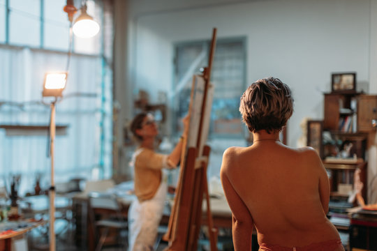 Woman painting model on canvas at her studio