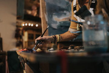 Woman painting model on canvas at her studio