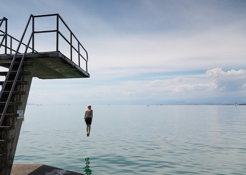 Rear view of boy jumping from diving platform into lake