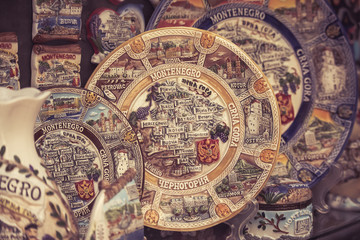 Fototapeta na wymiar Old Budva, Montenegro - July 19, 2019: Colorful painted plates and spoons showing the map of Montenegro at a souvenir stall in the old city of Budva, Balkan countries, South-East Europe.