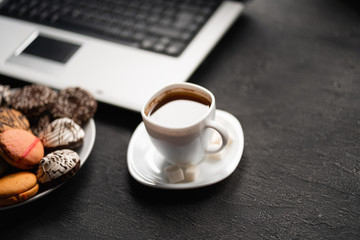 Office workplace. Desk table with laptop computer, cup of coffee and treats. Top view with copy space
