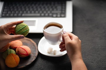 Unhealthy snack at work time. Woman eating cookies and drinking coffee at workplace. High calorie, fattening junk food, weight gain