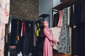 Arab woman in traditional Muslim clothes buys a new dress in an Oriental store.