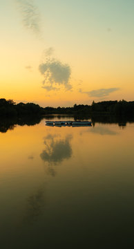 tranquil, twilight sunset shot over lake with reflections of sky and clouds in water and rowing boats to centre of lake