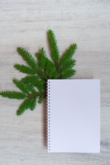Christmas minimal composition.  Notebook and fir dranches on wooden background, the place of the decal. Christmas, winter, new year concept. Flat lay, top view, copy space, square
