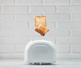 Roasted toast bread popping up of stoaster with white brickwall