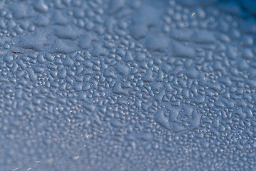 Morning dew droplets condensed on the metal surface of a car