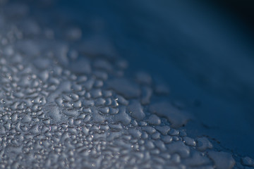 Morning dew droplets condensed on the metal surface of a car