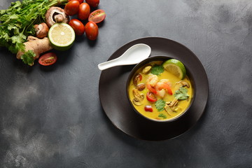 Tom Yam kung Spicy Thai soup with shrimp, seafood,tomatoes, mushrooms, lemongrass, coconut milk, ginger and chili pepper in bowl . Traditional Thai food