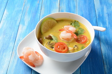 Tom Yam kung Spicy Thai soup with shrimp, seafood,tomatoes, mushrooms, lemongrass, coconut milk, ginger and chili pepper in bowl . Traditional Thai food