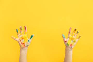 Child's hands in paint on color background