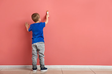 Little boy painting on color wall