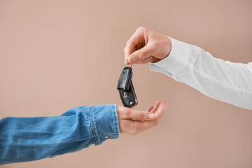 Salesman giving car keys to woman on color background