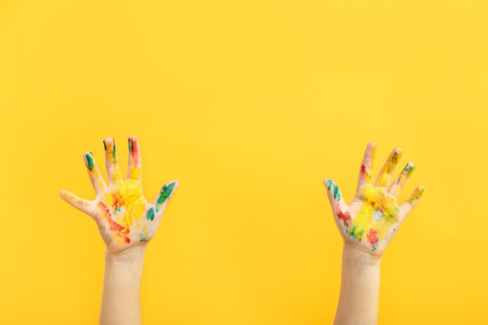 Child's hands in paint on color background