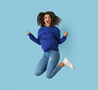 Jumping African-American woman on color background