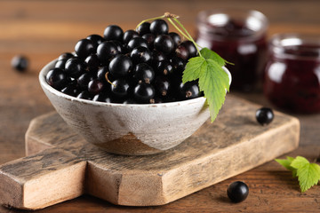 Black currant in bowl on wooden background