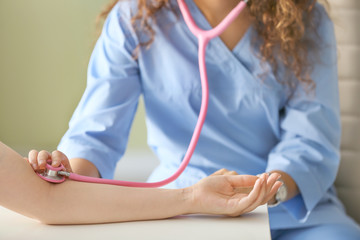 Doctor measuring pulse of young woman in clinic