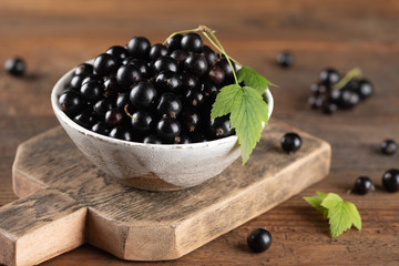 Black currant in bowl on wooden background