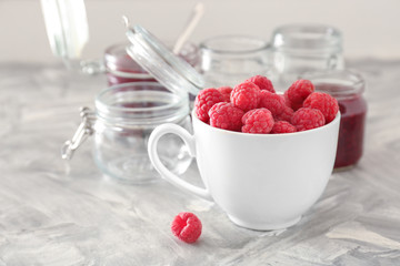Cup with fresh raspberries on grey table