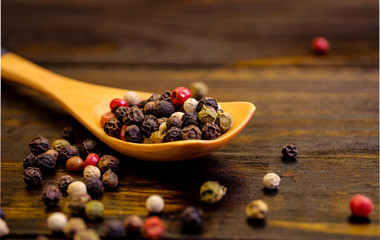 Spice. Mix of peppers in a wooden spoon, on a wooden table. Food concept.