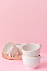 Ceramic cups on color background