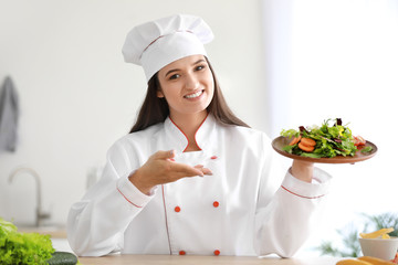 Beautiful female chef with salad in kitchen