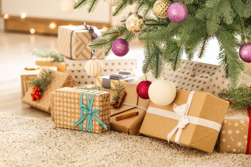 Beautiful gift boxes under fir tree in room