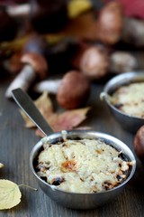 Julienne with forest mushrooms. Mushrooms are baked in cream and with cheese. Autumn leaves.