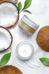 Jars of body cream and coconut on light background