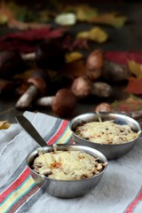 Julienne with forest mushrooms. Mushrooms are baked in cream and with cheese. Autumn leaves.