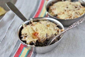 Julienne with forest mushrooms. Mushrooms are baked in cream and with cheese. Autumn leaves.