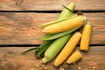 Fresh corn cobs on wooden background