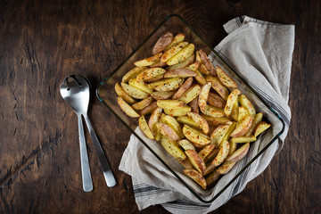 Baked potato in a plate on a wooden background, top view