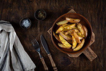 Baked potato in a plate on a wooden background, top view