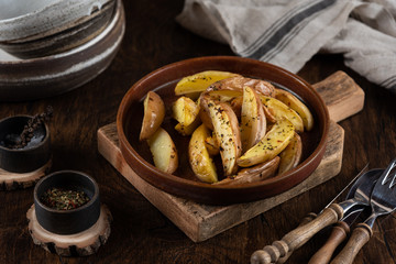 Baked potato in a plate on a wooden background, top view