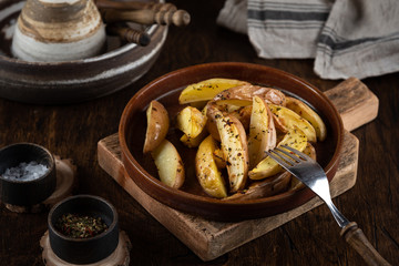 Baked potato in a plate on a wooden background, top view