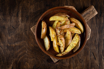 Baked potato in a plate on a wooden background, top view