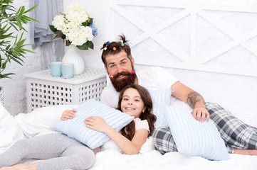 Obraz na płótnie Canvas Father bearded man with funny hairstyle ponytails and daughter in pajamas. Dad and girl relaxing in bedroom. Pajamas style. Having fun pajamas party. Slumber party. Happy fatherhood. Close friends
