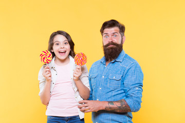 Sharing sweets with dearest people. Daughter and father eat sweet candies. Sweet childhood. Girl child and dad hold colorful lollipops. Sweet dessert. Bearded hipster good daddy for adorable daughter