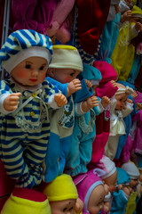 Muñecas de juguete, hechas de plástico y con coloridos vestidos, exhibidas en un típico mercado de mexico