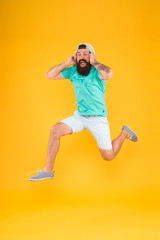 Fototapeta na wymiar Happy music. Happy hipster jumping on music on yellow background. Bearded man enjoying song playing in headphones with smile on happy face. Happy fun and upbeat