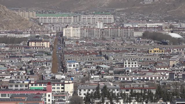 Main road with traffic cuts through residential and commercial neighborhood in modern part of Lhasa, development infrastructure and political influence in Tibet