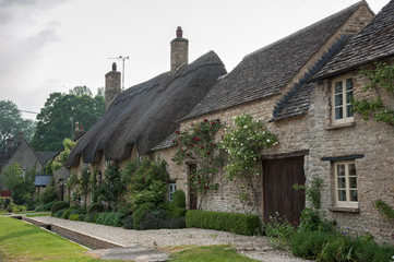Fototapeta na wymiar Narrow lane with romantic thatched houses and stone cottages in the lovely Minster Lovell village, Cotswolds, Oxfordshire, England 
