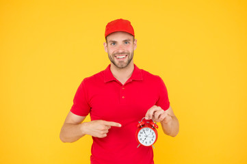 Always in time. Happy man with alarm clock on yellow background. Delivering your purchase. Courier service delivery. Salesman and courier career. Courier and delivery service. Postman delivery worker
