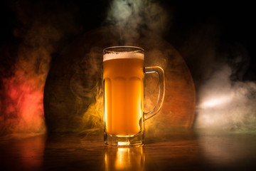 Beer glass on wooden table at dark toned foggy background